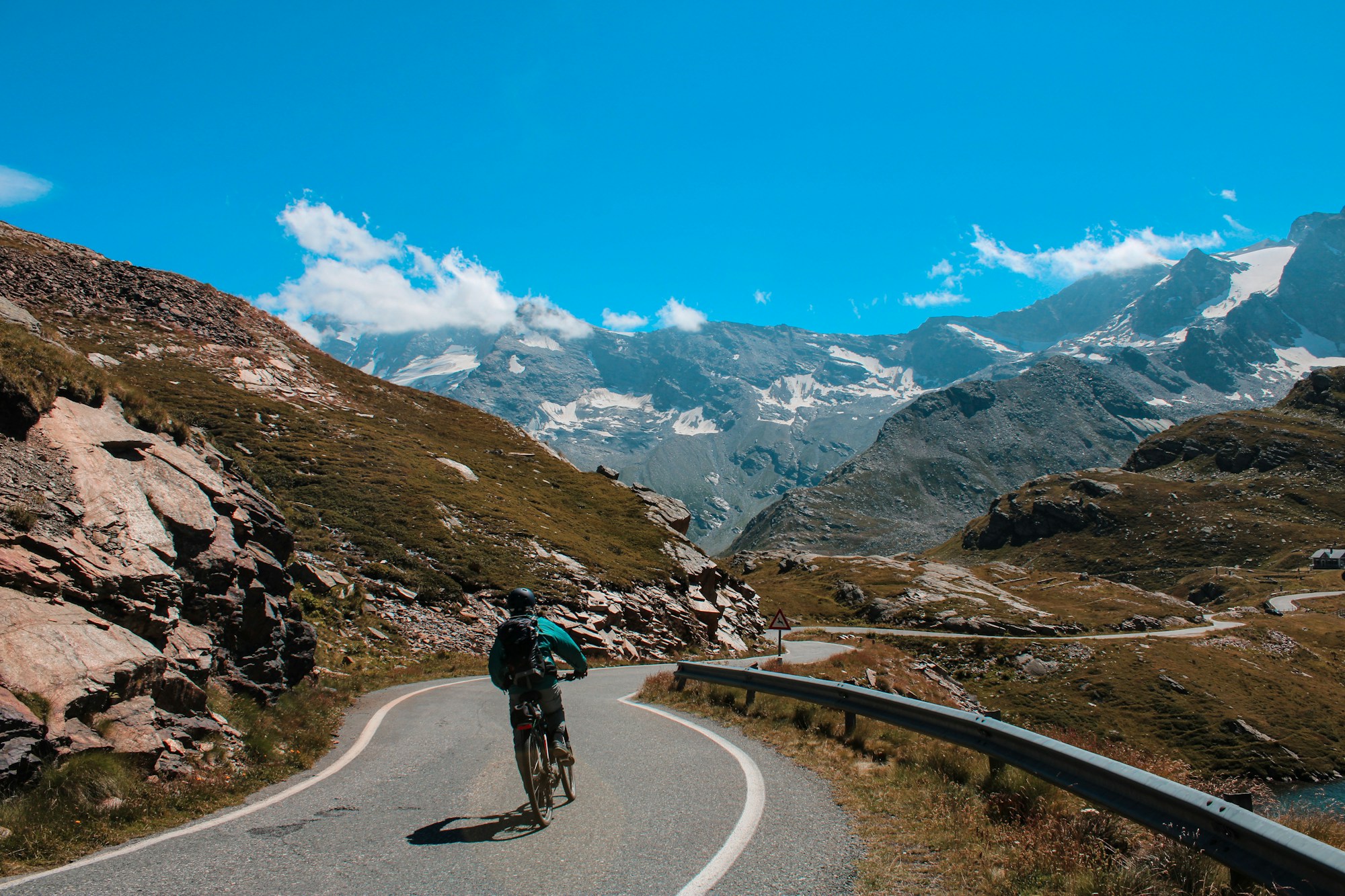 A cyclist following a winding road through the mountains